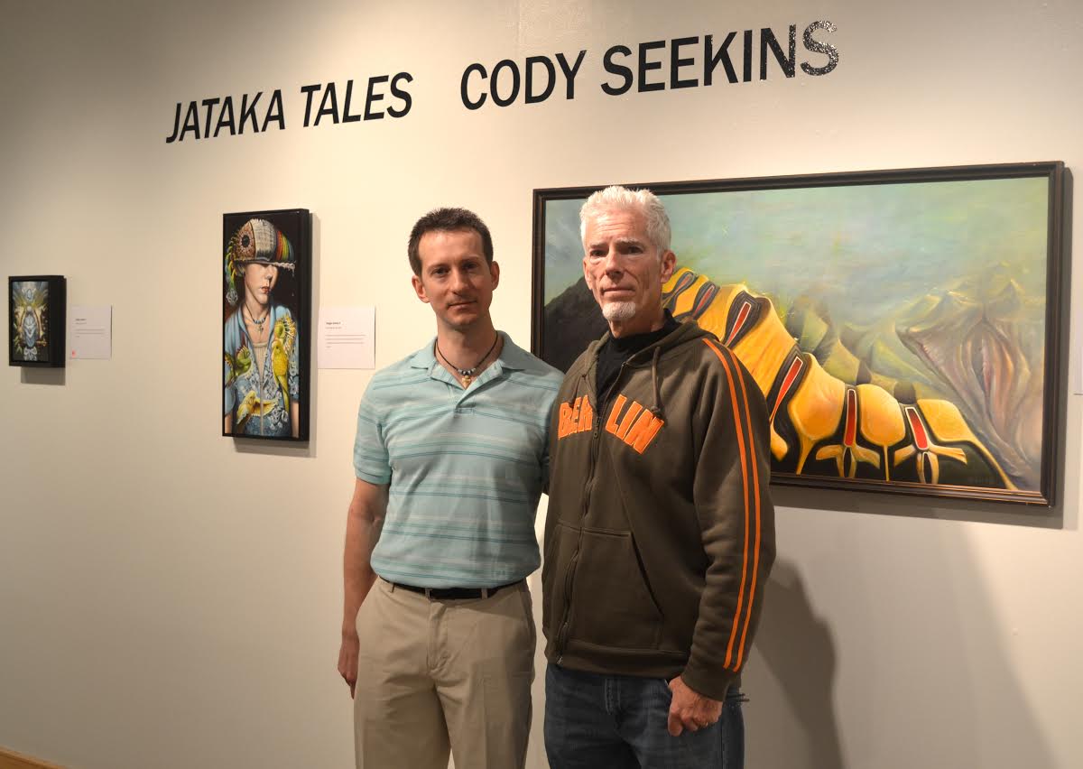 Cody Seekins standing with Christopher Gulick among Cody's paintings